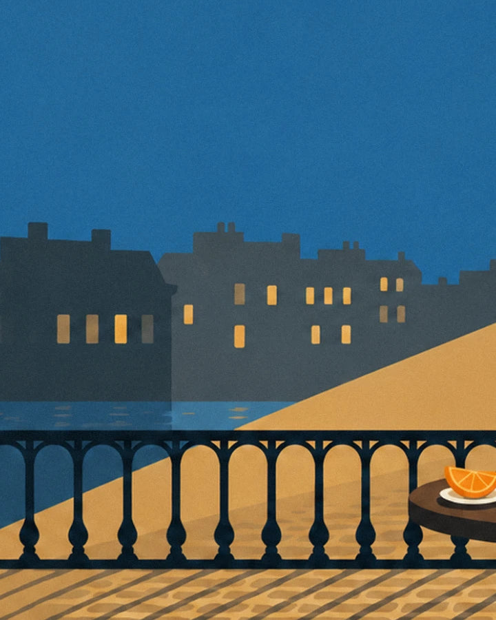 La balustrade noire de la terrasse, les façades aux fenêtres allumées et une tranche d'orange sur la table