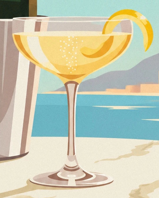The glass of golden cocktail with fine bubbles, garnished with a long twist of lemon peel