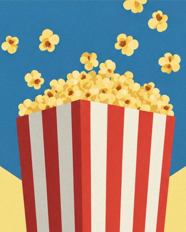 Il cono a righe che trabocca di popcorn dorati, con pezzetti sparsi sullo sfondo blu