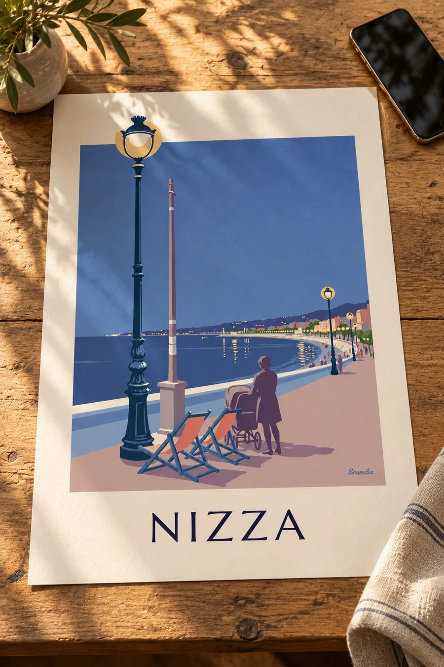 Poster sdraio e lampione di fronte alla Baia degli Angeli di sera: appoggiato su un tavolo